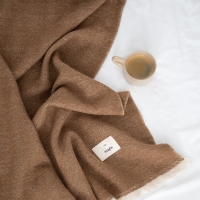 MOYHA Wolldecke Herringbone Haselnussbraun 130x170 cm auf einem Sofa