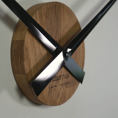 3D Wanduhr XXL Eiche Natur 100-130 cm mit schwarzen Zeigern vor weißer Wand 2